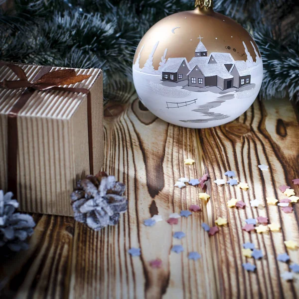 Noel süslemelerinin arka planında bir mum, koni ve meleğin yanında bir hediye duruyor..