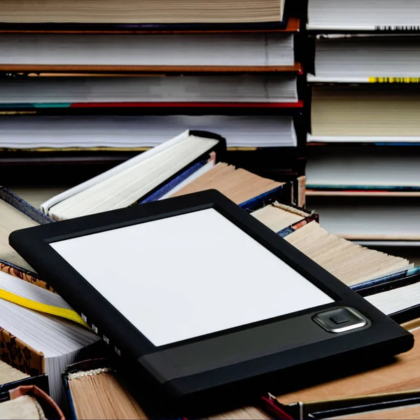 De e-boek met een wit scherm ligt op de open multi-gekleurde boeken die liggen op een donkere achtergrond, close-up — Stockfoto