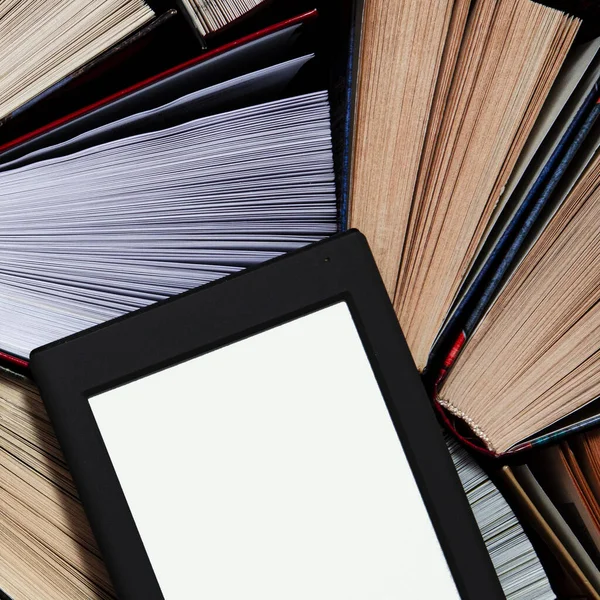 El libro electrónico con una pantalla blanca se encuentra en los libros multicolores abiertos que se encuentran sobre un fondo oscuro, primer plano — Foto de Stock