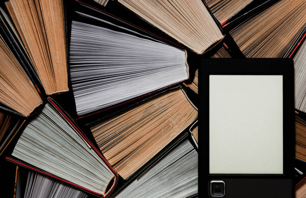 The e-book with a clean white screen rests on the open multi-colored books. ready to read