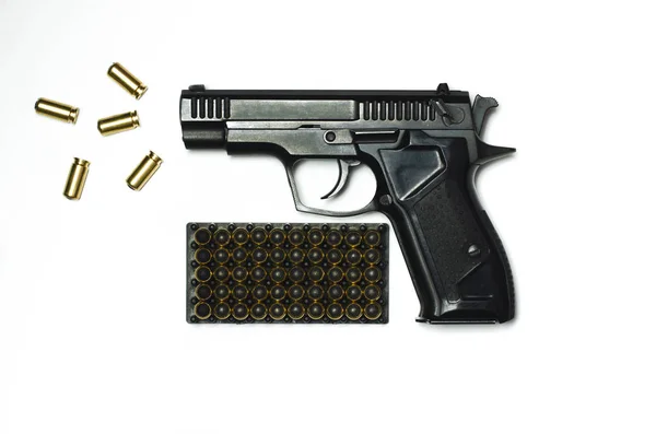 Чорний пістолет з кулями для стрільби лежить на білому тлі . — стокове фото