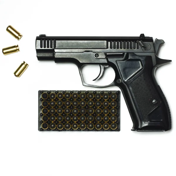Una pistola negra con balas para disparar yace sobre un fondo blanco. —  Fotos de Stock