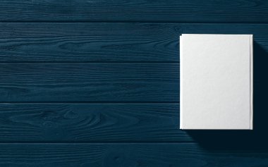 Beyaz kaplı kitap ahşap bir masanın üzerinde..