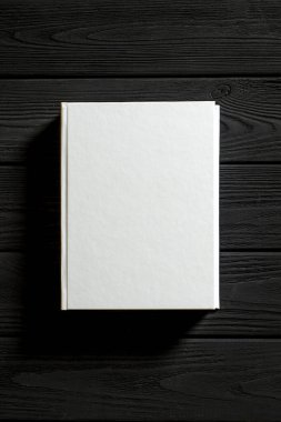 Beyaz kaplı kitap ahşap bir masanın üzerinde..