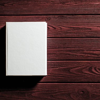 Beyaz kaplı kitap ahşap bir masanın üzerinde..