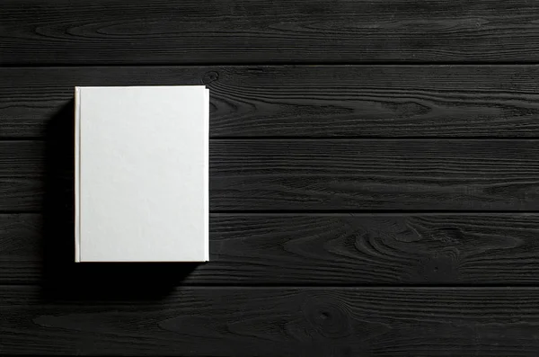 El libro de tapa blanca está sobre una mesa de madera texturizada . — Foto de Stock