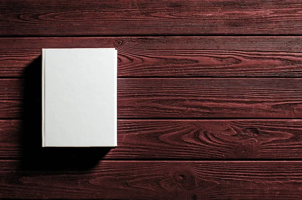 Beyaz kaplı kitap ahşap bir masanın üzerinde..