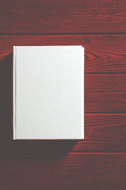 Beyaz kaplı kitap ahşap bir masanın üzerinde..