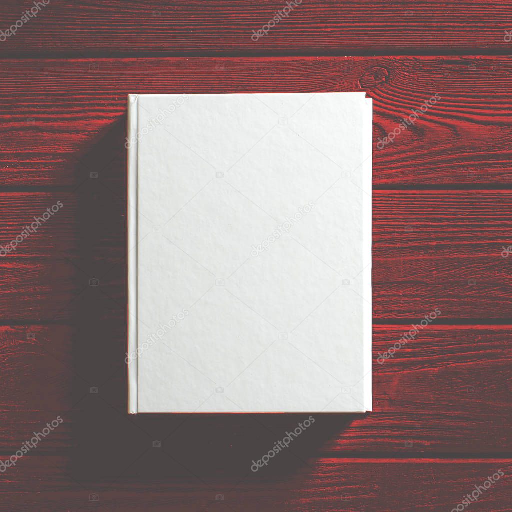 The white-cover book is on a textured wooden table.