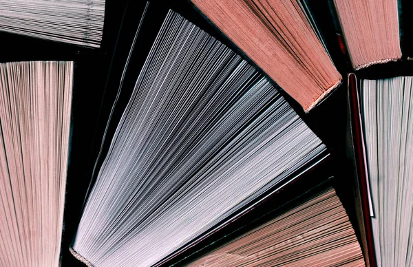 Könyvek. Sok színes, nyitott könyv áll sötét háttéren. — Stock Fotó