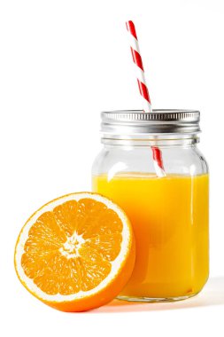 Taze sıkılmış portakal suyuyla dolu cam kavanoz taze portakalların yanında beyaz arka planda duruyor.