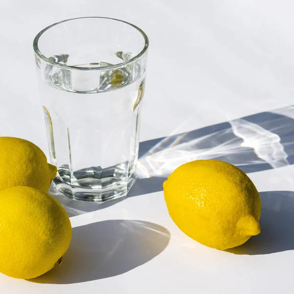 Water glass with strong shadows on white background — Stock Photo, Image