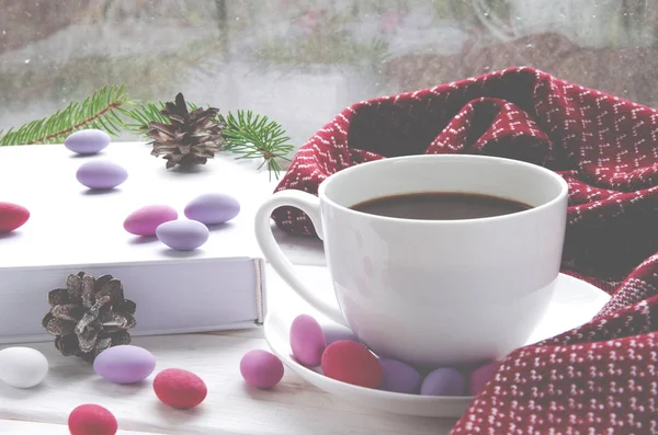 Casa acogedora naturaleza muerta: taza de café caliente y libro abierto con cuadros calientes en el alféizar de la ventana contra el paisaje de nieve exterior — Foto de Stock