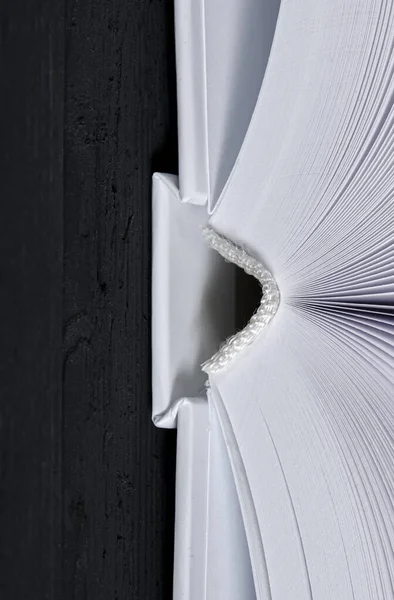 The white-cover book is on a textured wooden table.