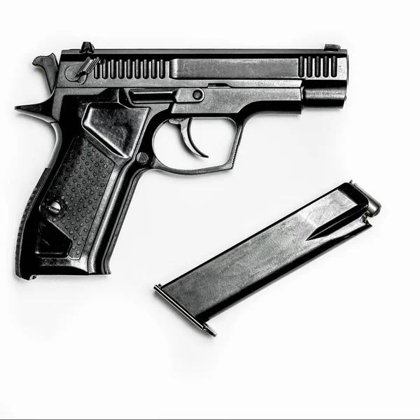 A black pistol with a magazine for cartridges lies on a white background — Stock Photo, Image