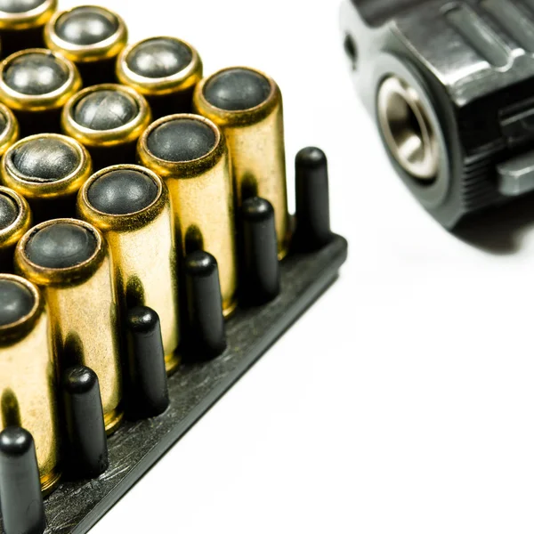 총을 쏘기 위해 총알이 들어 있는 검은 권총이 하얀 배경 위에 놓여 있다. — 스톡 사진