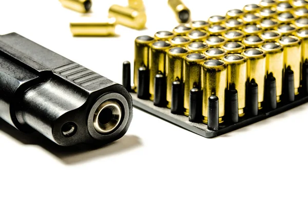 총을 쏘기 위해 총알이 들어 있는 검은 권총이 하얀 배경 위에 놓여 있다. — 스톡 사진