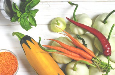 Hasat. Patisons, sarımsak, havuç, fesleğen, mercimek ve kabak ahşap bir masa üzerinde yalan