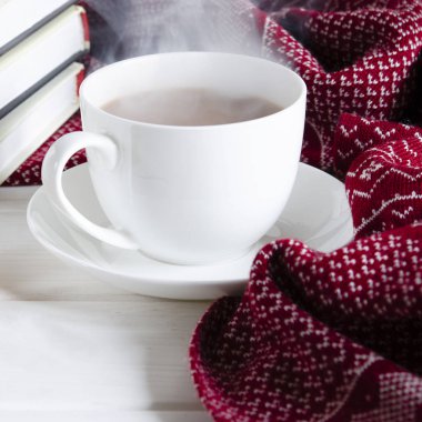 Bir fincan sütlü kahve, kitapların ve sıcak yün atkıların yanında.