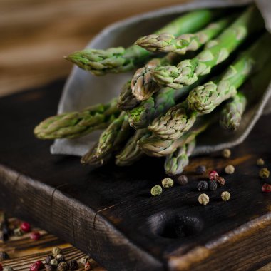 Vejetaryenler için yeşil diyet: sulu yeşil kuşkonmaz bir ağaç kesme tahtasının üzerinde yatıyor