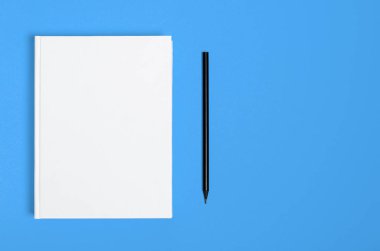 Mockup of closed blank square book and black pencil at colored textured paper background