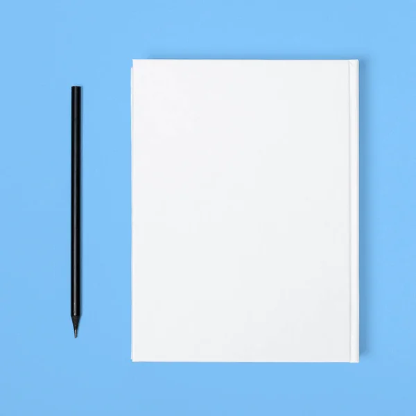 Mockup of closed blank square book and black pencil at colored textured paper background — 스톡 사진