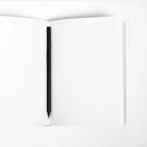 Mockup de libro cuadrado en blanco cerrado y lápiz negro en fondo de papel texturizado blanco —  Fotos de Stock