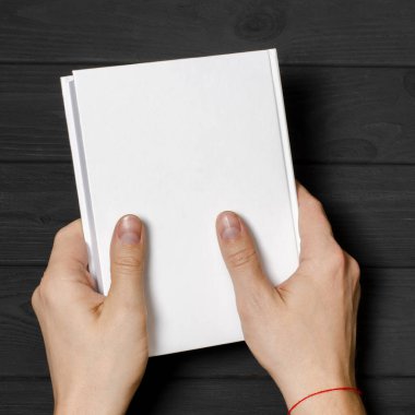 Men's hands holding closed book with blank cover on light background