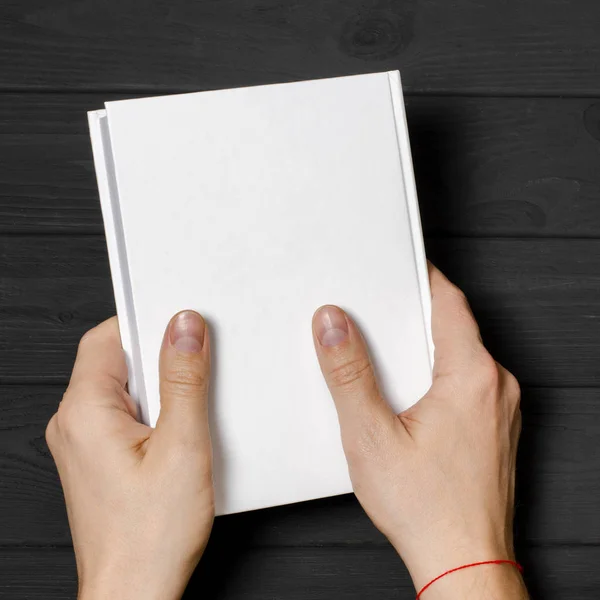 Mãos masculinas segurando livro fechado com tampa em branco no fundo claro — Fotografia de Stock