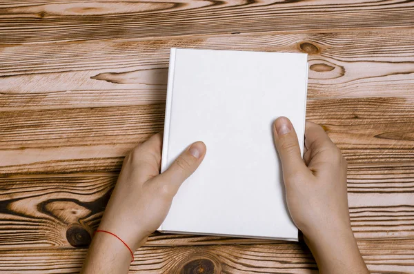 Men's hands holding closed book with blank cover on light background