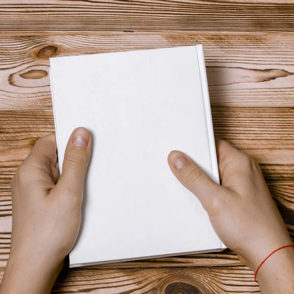 Mani da uomo che tengono chiuso il libro con copertina bianca su sfondo chiaro — Foto Stock