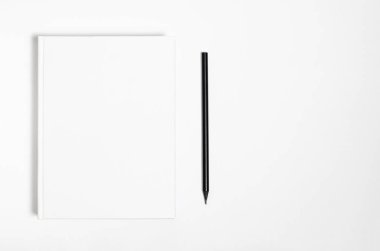 Mockup of closed blank square book and black pencil at white textured paper background