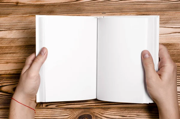 Чоловічі руки тримають відкриту книгу з порожньою обкладинкою на світлому фоні — стокове фото
