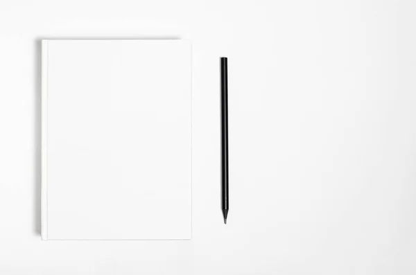 Mockup di chiuso libro bianco quadrato e matita nera su sfondo bianco carta strutturata — Foto Stock