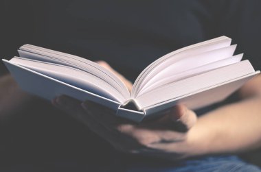 Erkeklerin elleri temiz sayfaları olan beyaz bir kitap tutuyor.