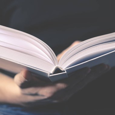 Erkeklerin elleri temiz sayfaları olan beyaz bir kitap tutuyor.