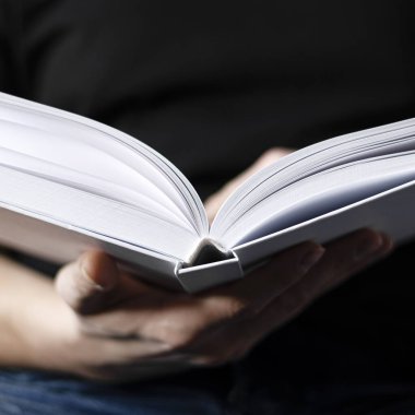 Erkeklerin elleri temiz sayfaları olan beyaz bir kitap tutuyor.