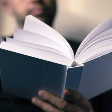 Erkeklerin elleri temiz sayfaları olan beyaz bir kitap tutuyor.