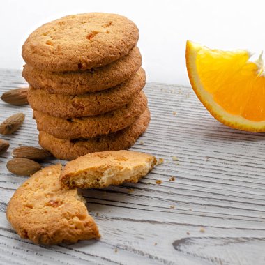 Yuvarlak, renkli meyveli turuncu bisküviler ve ahşap bir masada duran sulu bir dilim portakal.