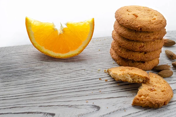 Круглые апельсиновые печенья с красочными засахаренными фруктами и ломтиком сочного апельсина, лежащего на деревянном столе — стоковое фото