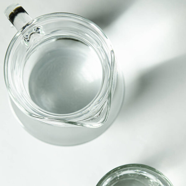 Pure clear water in a glass glass and glass jug stands on a white background