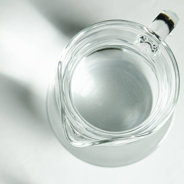 Pure clear water in a glass glass and glass jug stands on a white background