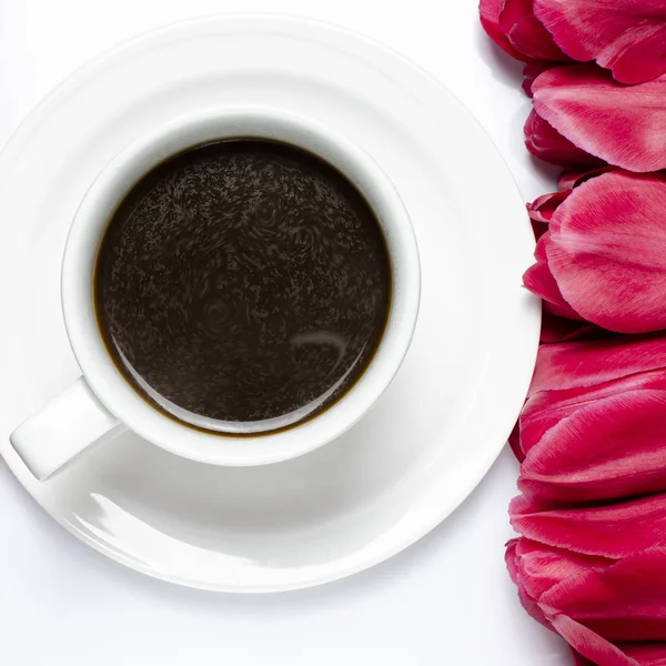 A cup of black coffee with red tulips on a white background Stock Picture