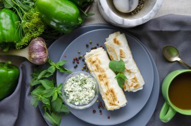 Sağlıklı kahvaltı: süzme peynirli ve dereotlu krepler yuvarlak bir tabakta yatıyor.