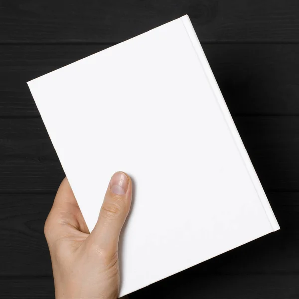 Men's hands holding closed book with blank cover on light background — Stok fotoğraf