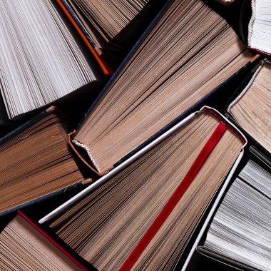 Kitaplar. Birçok renkli, kalın, açık kitap karanlık bir arka planda duruyor.