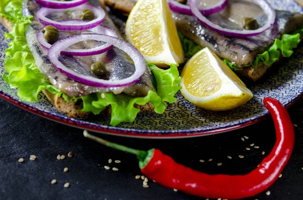 Sandwich herring on the plate, served with onions, parsley and lemon. Top view, healthy sea food. — Stok fotoğraf