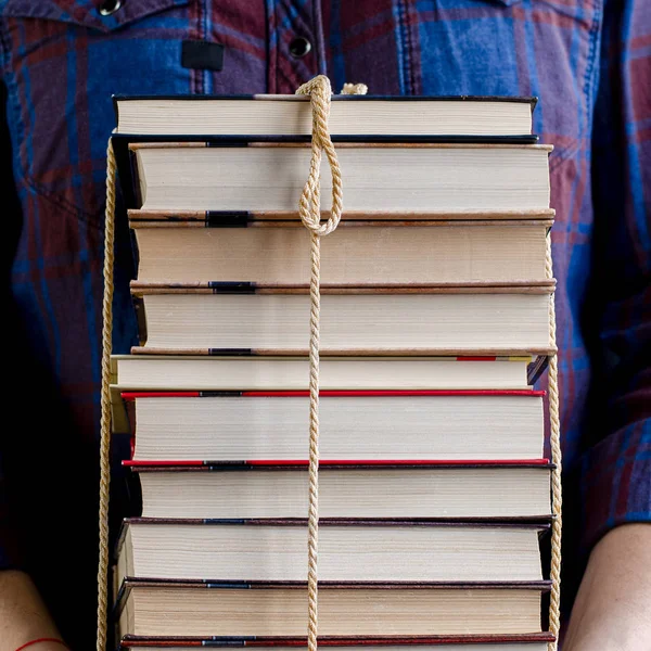 Человек держит много книг, связанных веревкой. — стоковое фото