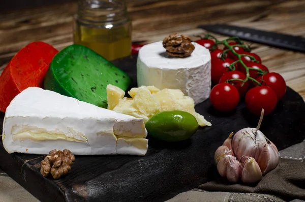 Сыр с различными сырами, оливки, чили, багет и мясо лежит на деревянной доске — стоковое фото