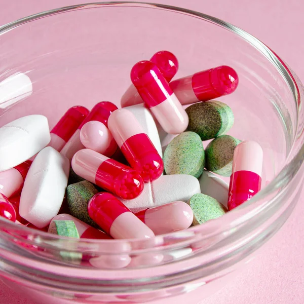 Multi-colored anti-virus tablets of different shapes lie in a glass container